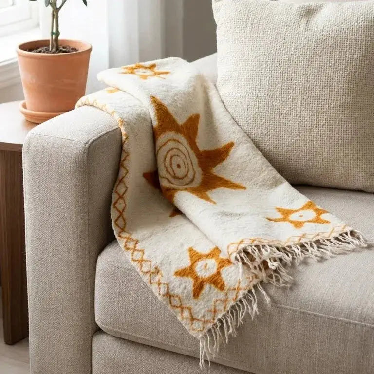Plaid beige motif soleil orange à franges posé sur canapé tissu beige clair et coussin