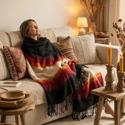 Femme relaxant sur canapé décoré avec plaide coloré et ambiance chaleureuse avec bougies et lampe