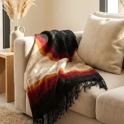 Plaid douillet en laine avec dégradé noir, rouge et beige sur canapé beige dans salon lumineux