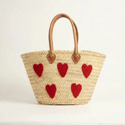 Woven straw tote bag with tan leather handles and five red heart-shaped patches on front
