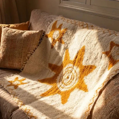 Plaid beige avec motif soleil doré sur canapé avec coussins texturés dans salon lumineux