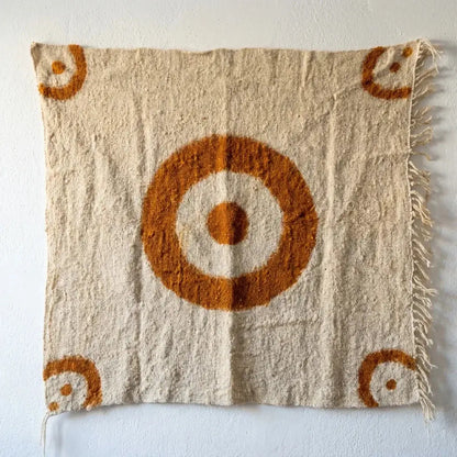 Tapis mural fait main en laine beige avec motifs ronds orange, tissu texturé et franges à droite