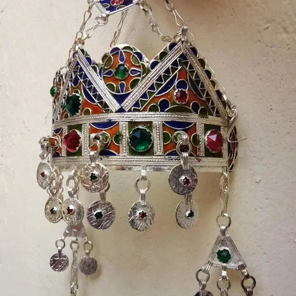 Bijou pendentif en métal argenté avec émail bleu, rouge et vert et pierres colorées sur fond clair